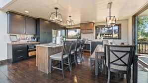 A modern kitchen with dark cabinetry, a central island, and pendant lighting. - Altitude Adjustment (Lead)
