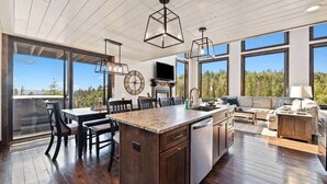 A spacious kitchen with a central island, large windows, and a dining area with chairs. - Altitude Adjustment (Lead)