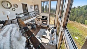 A spacious living area with a fireplace, large windows, and a view of the outdoors. - Altitude Adjustment (Lead)