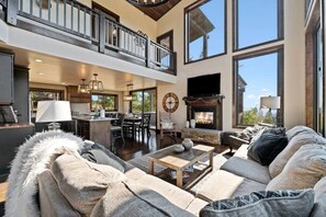 A spacious living room with a fireplace, a dining area, and a kitchen. - Altitude Adjustment (Lead)