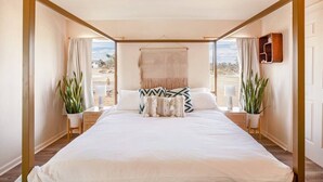 Quarto espaçoso com uma cama grande, duas mesas de cabeceira e vista para o exterior.