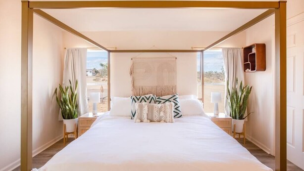 A spacious bedroom with a large bed, two bedside tables, and a view of the desert landscape.
