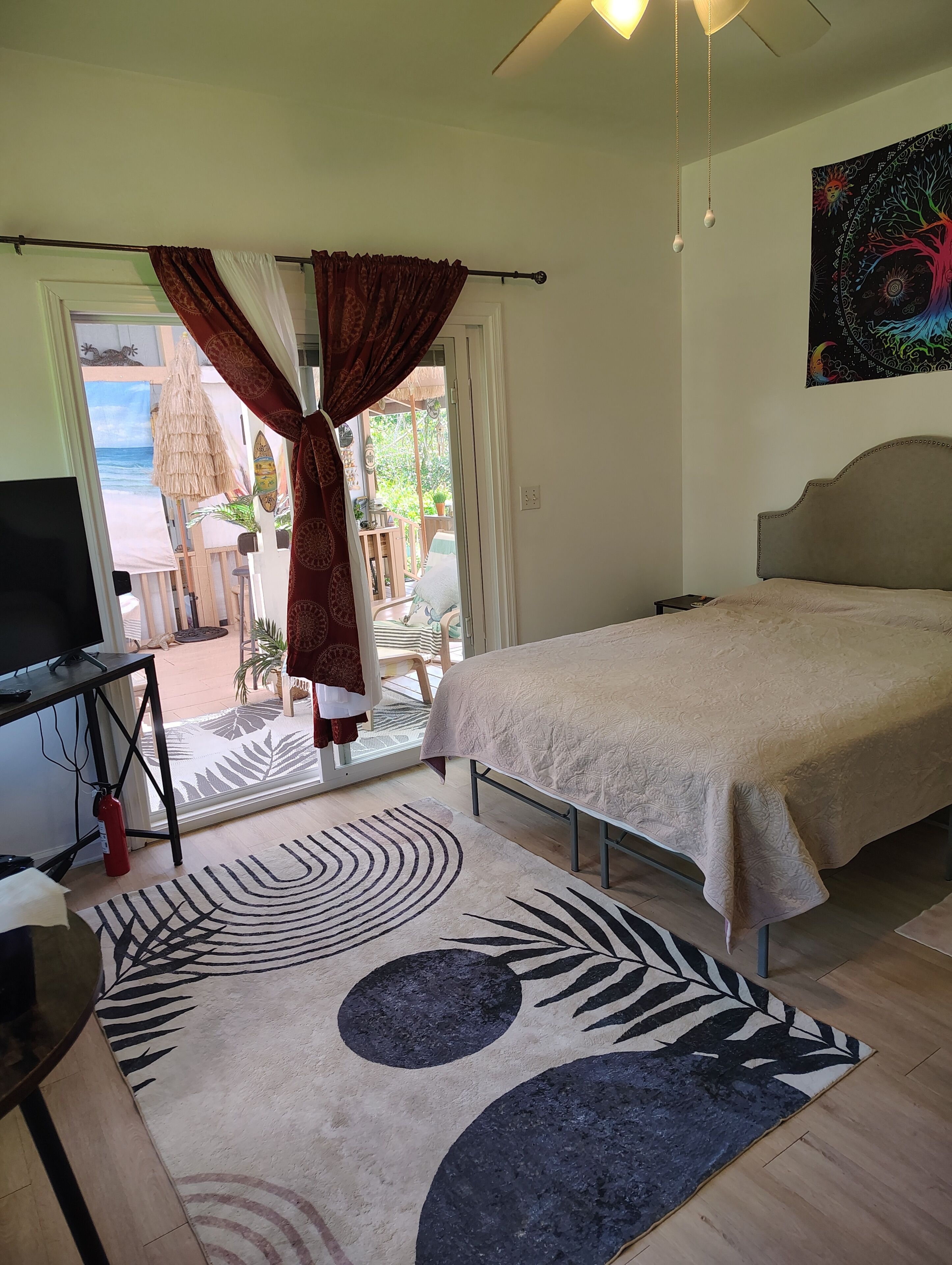 Un dormitorio con cama, televisión, puerta que da a un balcón y vista al mar.