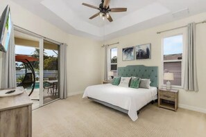 A bedroom with a bed, a ceiling fan, a nightstand, and a window. - Orange Oasis - A Private Tropical Paradise (Cape Coral)