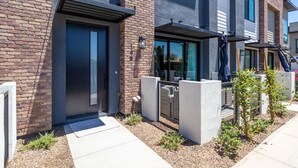 A modern apartment building with a brick facade, large windows, and a gated entrance. - 3 Bedroom Townhome in the heart of downtown Gilbert, AZ - Lot 30 (Gilbert)