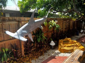 Stroll through the serene garden, surrounded by lush greenery and a unique shark sculpture.