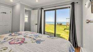 Un dormitorio con una cama grande, vistas al mar y una puerta que da a un balcón.