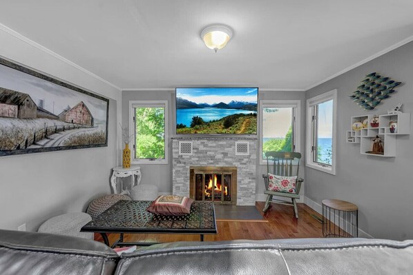 A living room with a fireplace, a sofa, a coffee table, and a view of a lake through the windows.