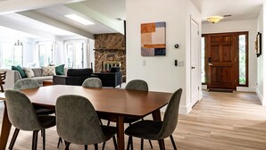 A modern living room with a stone fireplace, a dining area with a wooden table and chairs, and a hallway leading to a wooden door. - Modern Sedona Escape Rooftop Views, Trails Nearby, Pet Friendly (Sedona)