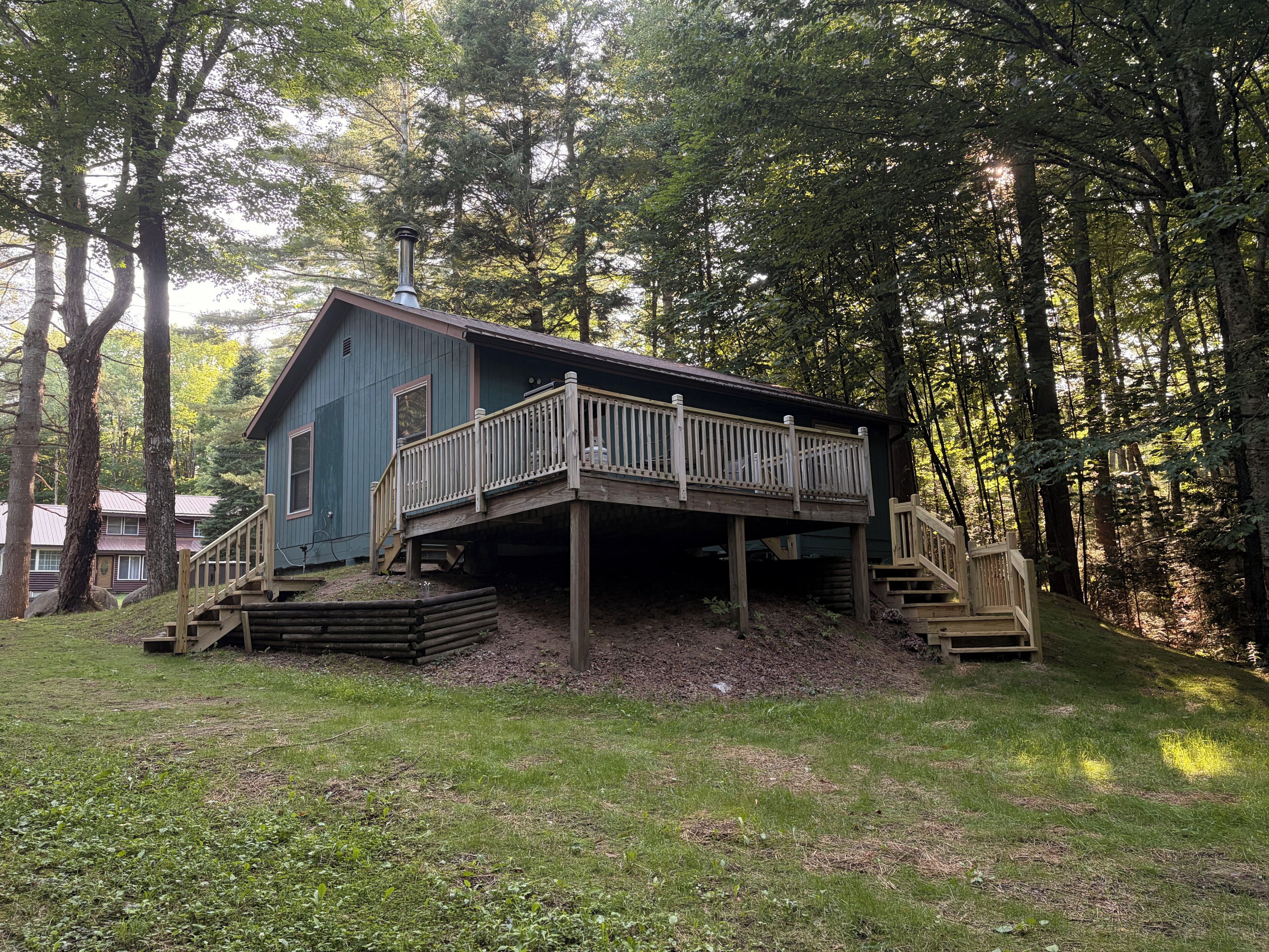 A cabin with a wooden deck and stairs leading to a covered porch.
