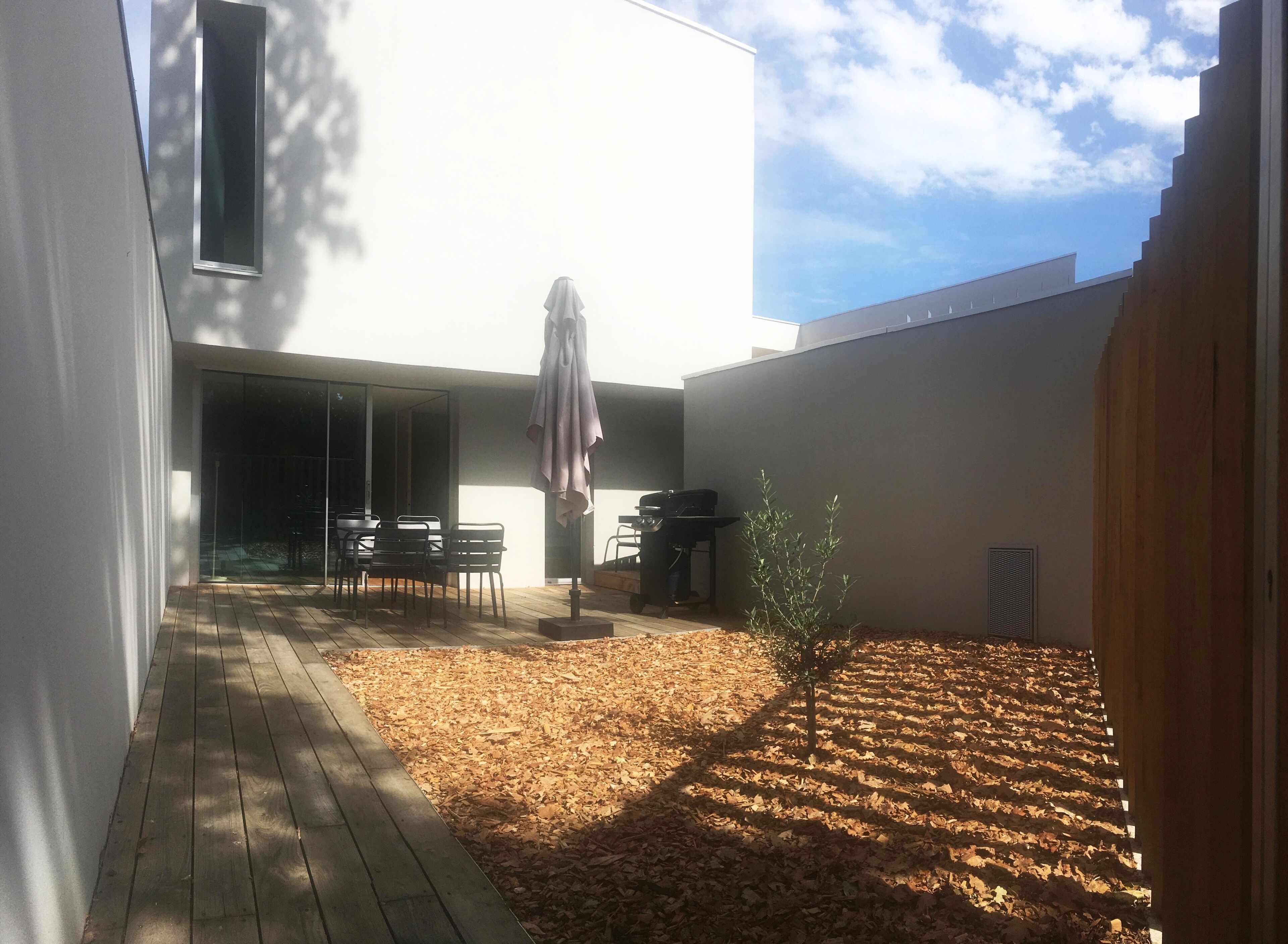 Eine moderne Terrasse mit Holzboden, einem Grill und einer kleinen Pflanze.