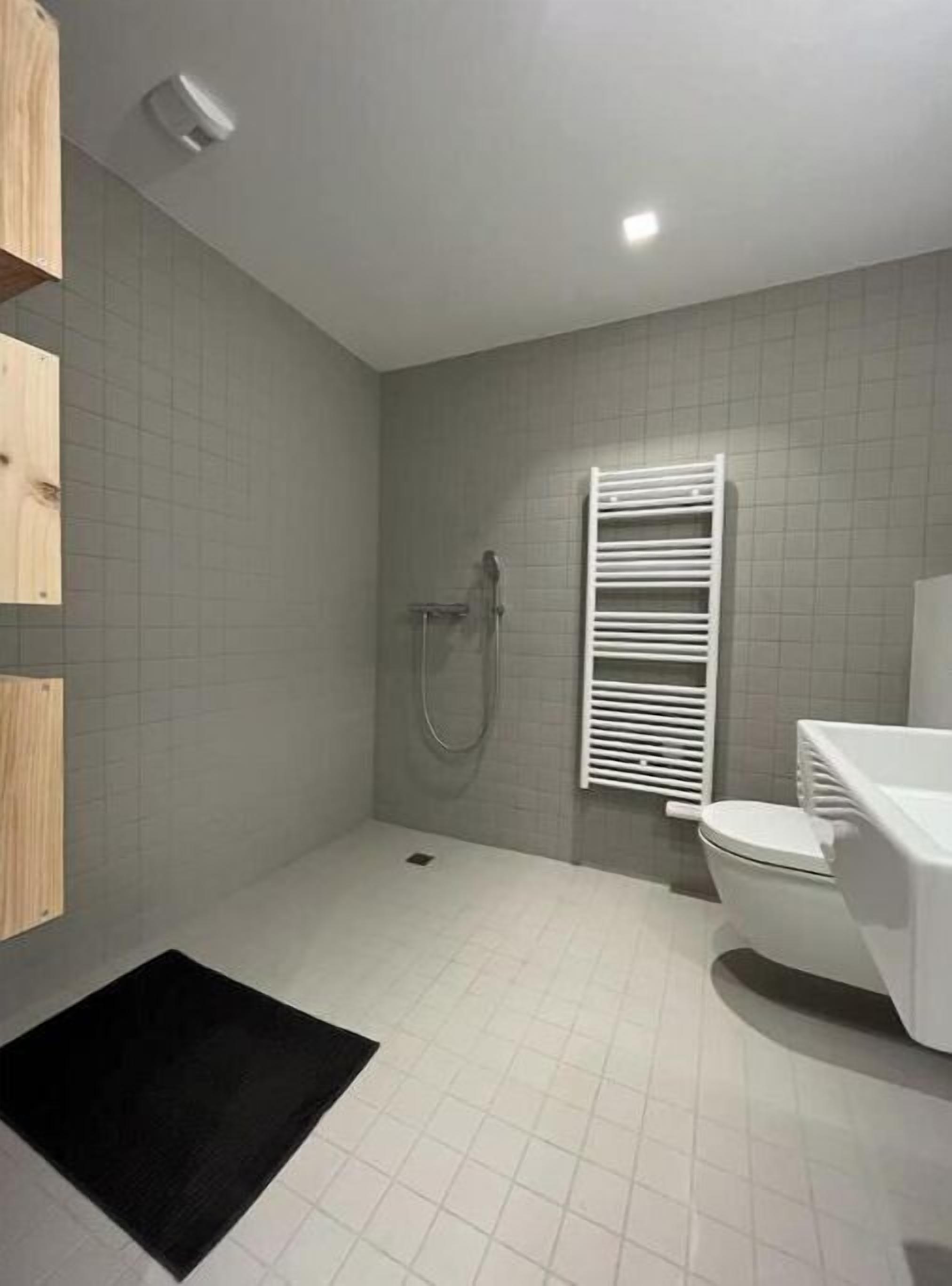 Une petite salle de bain avec une douche, des toilettes et un porte-serviettes.