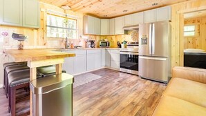 Een moderne keuken met houten kastjes, een roestvrijstalen koelkast en een eethoek met een bank.