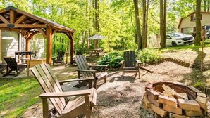 Een overdekt buitengebied met Adirondack-stoelen, een vuurkorf en een barbecue.