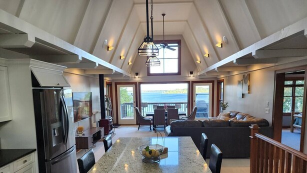 A spacious kitchen with a large island, a refrigerator, and a dining area with a view of the ocean. - Luxury Lakefront Retreat, Hot Tub, Game Room, Views (Nisswa)