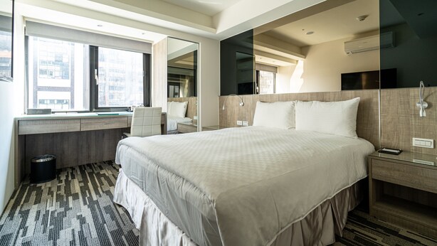 A modern hotel room with a large bed, a desk, a chair, a small trash bin, and a large window offering a city view. - Hotelshere Taipei (Taipei)