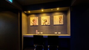 A reception area with a counter, two chairs, and three framed artworks on the wall. - Hotelshere Taipei (Taipei)