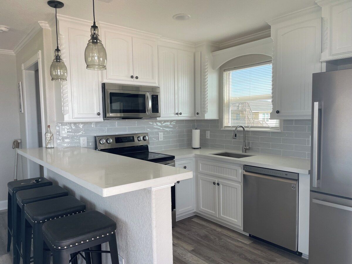 A kitchen with white cabinetry, a stainless steel refrigerator, a microwave, and a dishwasher.