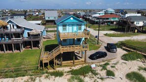 Une propriété située en bord de mer, comprenant une maison à deux étages dotée d’un balcon et d’une terrasse en bois.