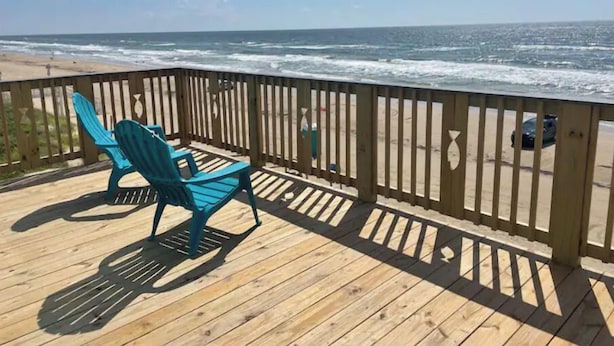 A wooden deck with a blue chair overlooking a beach.