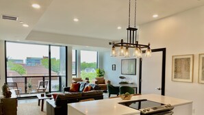 A modern kitchen with a central island, stainless steel appliances, and a dining area with a view of the city.