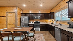 A modern kitchen with wooden walls, stainless steel appliances, and a granite countertop.