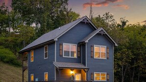A two-story house with a balcony, a porch with chairs, and a sign indicating a rental price.