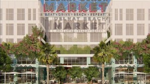 A Delray Beach Market building with a clear sign, surrounded by palm trees and outdoor seating areas.