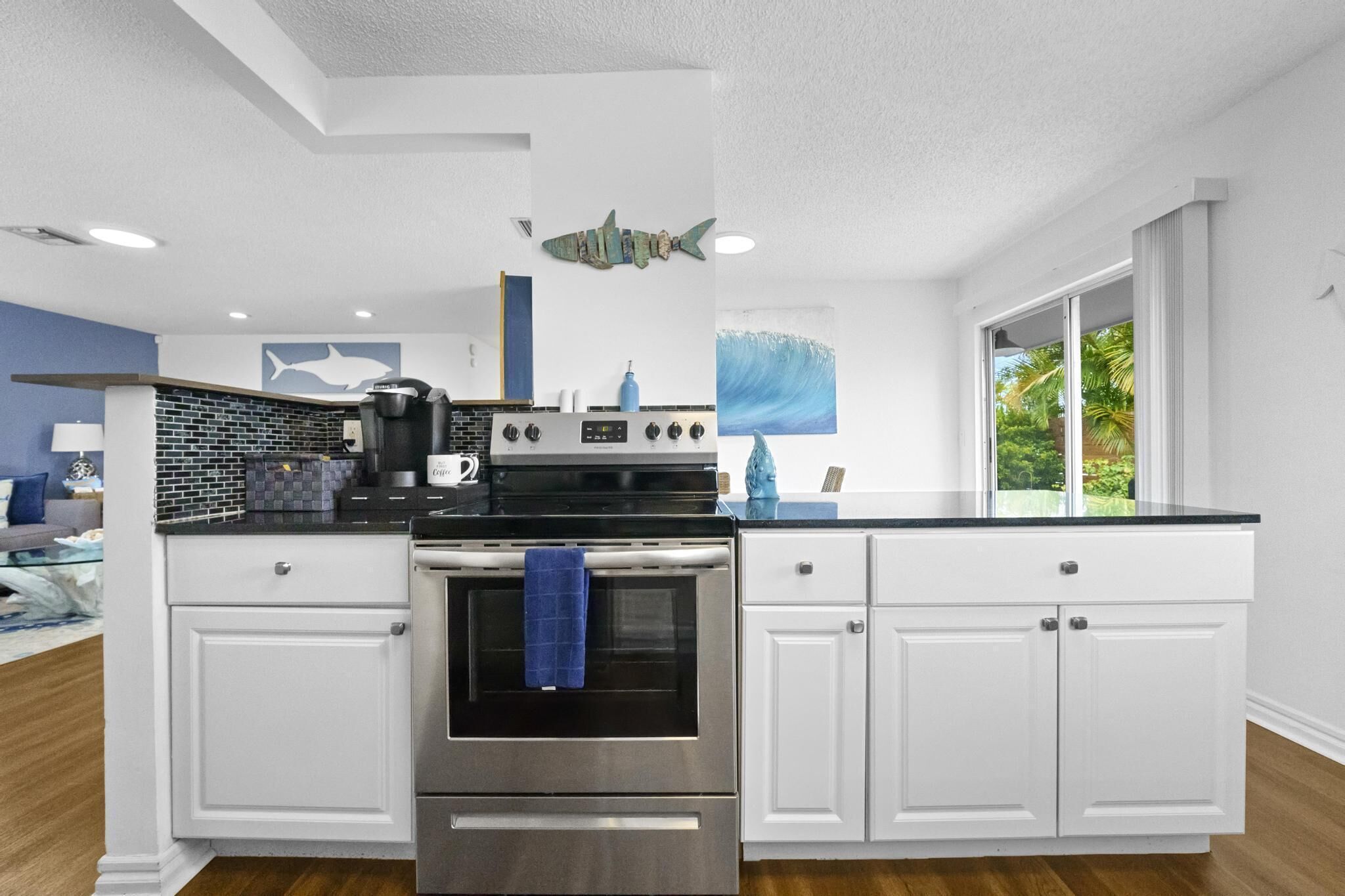 A modern kitchen with white cabinets, a stainless steel oven, and a black countertop.