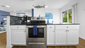 A modern kitchen with white cabinets, a stainless steel oven, and a black countertop.