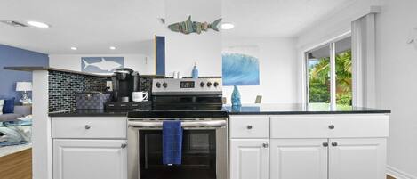 A modern kitchen with white cabinets, a stainless steel oven, and a black countertop.