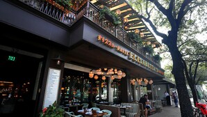 An outdoor seating area with tables and chairs, a sign for 'PIZZA PASTA ELISABETTA'S', and a menu board listing various dishes.