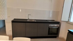 Eine moderne Küche mit schwarzem Arbeitsplatz, Spüle aus Edelstahl und eingebautem Ofen.