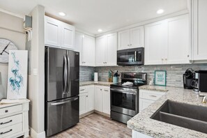 A modern kitchen with white cabinets, stainless steel appliances, and a granite countertop.