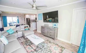 Relax in this spacious living room with a large sectional sofa, flat-screen TV, and wooden cabinet.