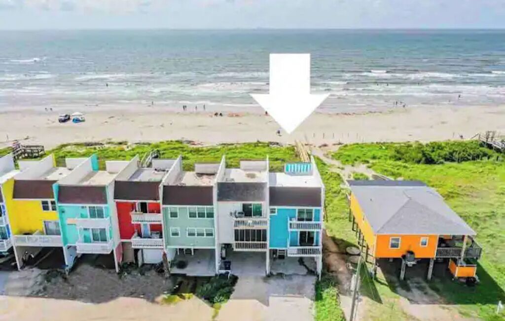 Una proprietà fronte spiaggia con case colorate, vista mare e una scalinata che conduce alla spiaggia.