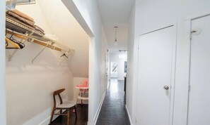 A narrow hallway with a white door, a baby changing station, and a clothes drying rack.