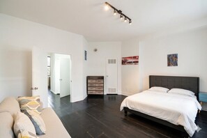 A bedroom with a bed, a dresser, a nightstand, and a door leading to another room.