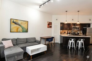 En moderne stue med en grå sofa, et hvidt sofabord og et billede af en påfugl på væggen.