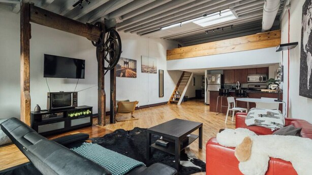 A spacious living area with a wooden ceiling, a television, a fireplace, and a kitchen in the background. - ☆ LUXURIOUS OLD CITY PENTHOUSE ☆ (Philadelphia)