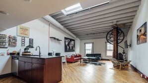 A spacious loft with a high ceiling, wooden flooring, a kitchen area, a dining table, and a large window. - ☆ LUXURIOUS OLD CITY PENTHOUSE ☆ (Philadelphia)