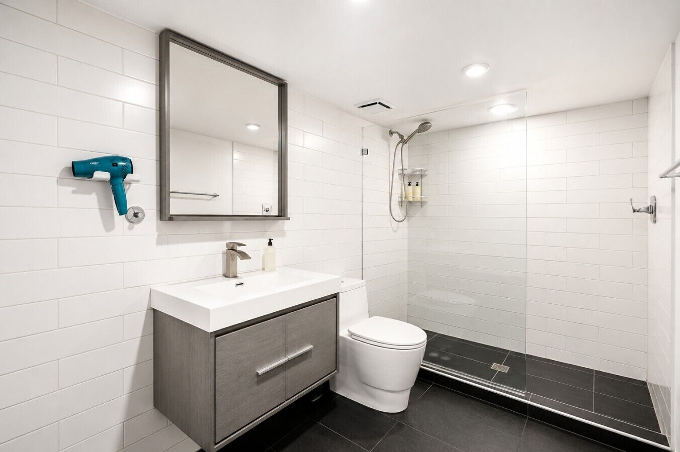 A modern bathroom with a white sink, a mirror, a toilet, and a shower area.