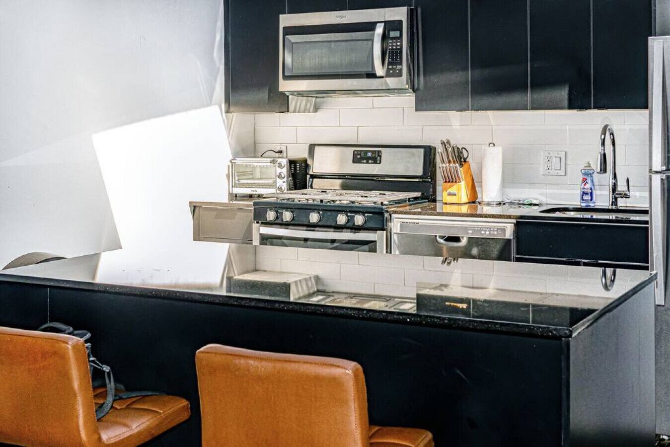A modern kitchen with a central island, black cabinets, a microwave, a toaster, and a stove.