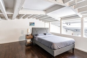 Une chambre à coucher avec un lit, une table de chevet et un tableau accroché au mur.