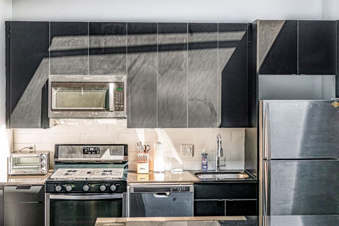A kitchen with a microwave, stove, oven, toaster, sink, and refrigerator.