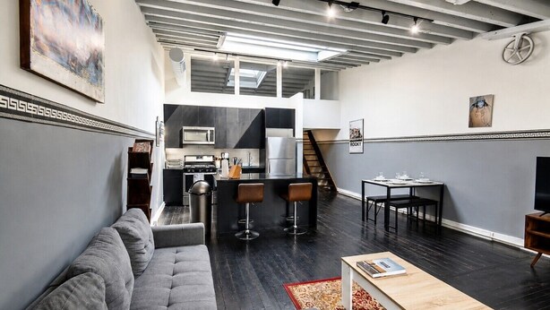 A modern loft-style apartment with a kitchen, dining area, and living room.