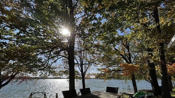A wooden deck with a table and chairs overlooking a lake. - Cottages on Sand Lake - The Lazy Lakehouse (Nottawa)