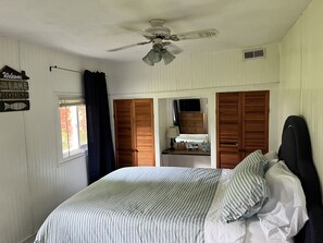 Relax in this cozy retreat with a large bed, ceiling fan, and window with a view.