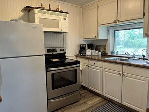 Prepare meals in the compact kitchen with a refrigerator, microwave, and double oven, featuring a sink and window with an outdoor view.