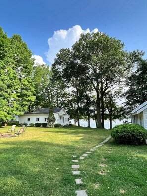 Traditional home with a gabled roof and chimney, set amidst mature trees and a well-manicured lawn.